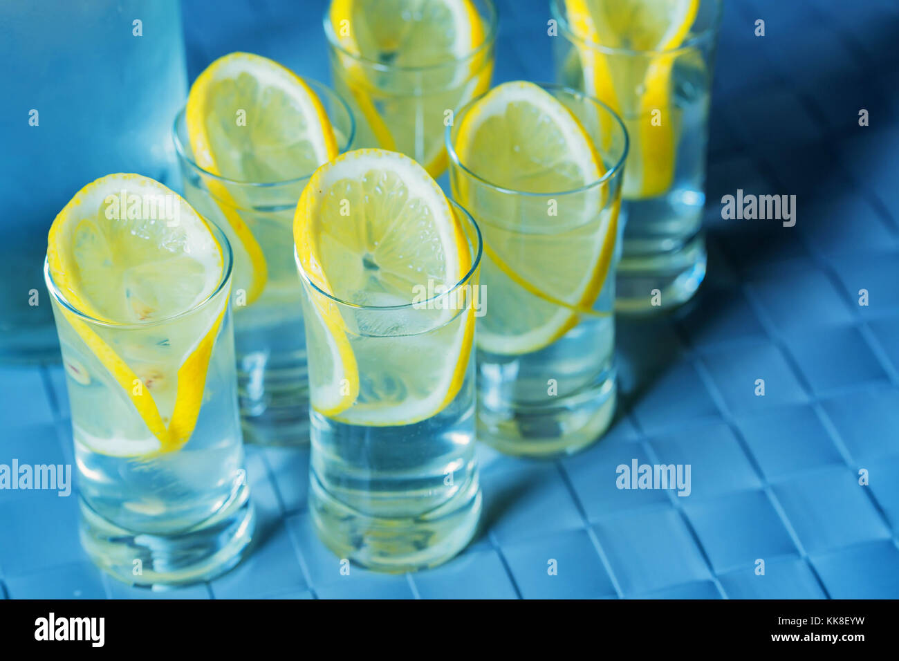 Vodka shot glass and lemon on blue surface Stock Photo Alamy