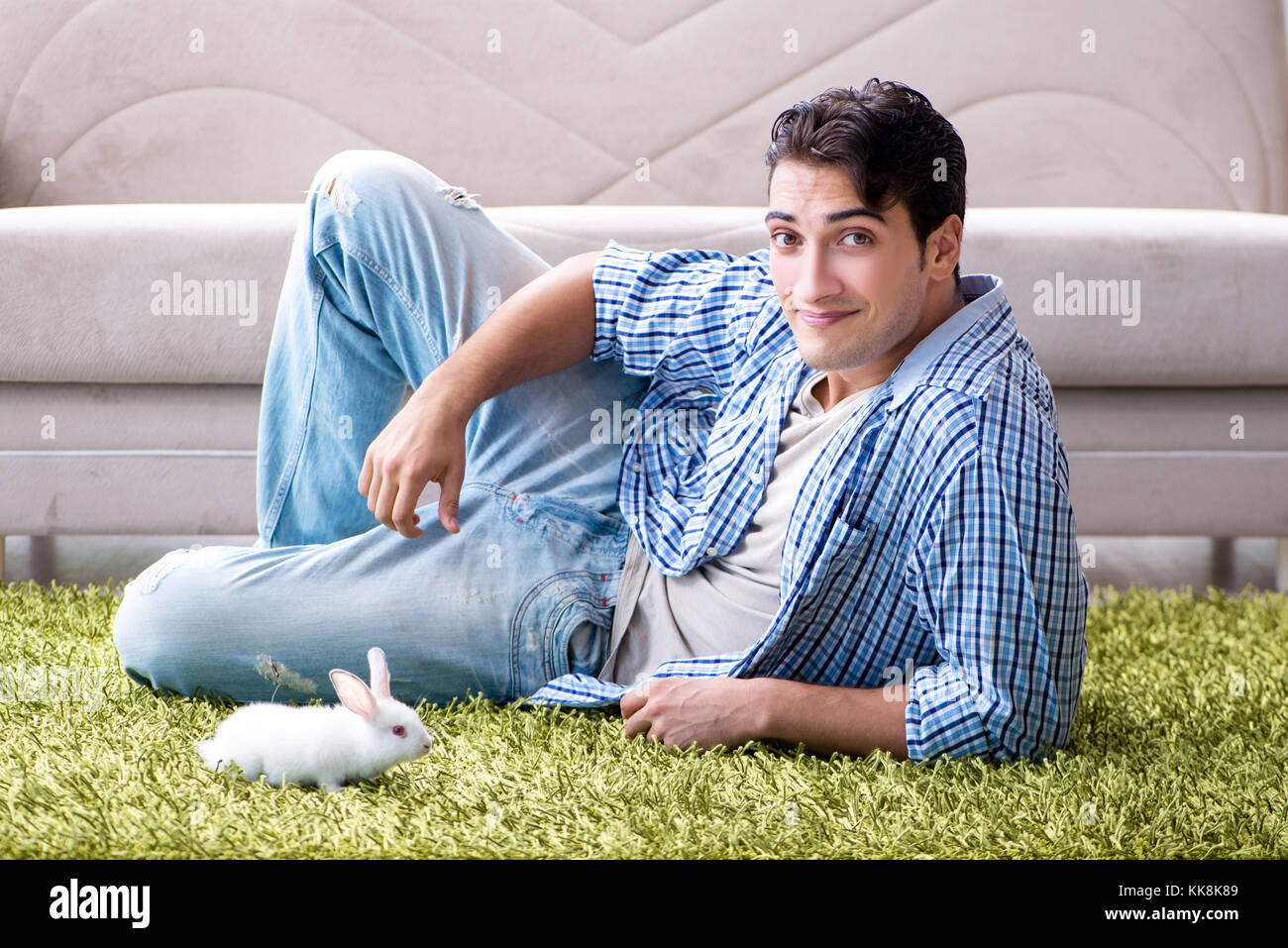 Young man playing with pet rabbit at home Stock Photo - Alamy