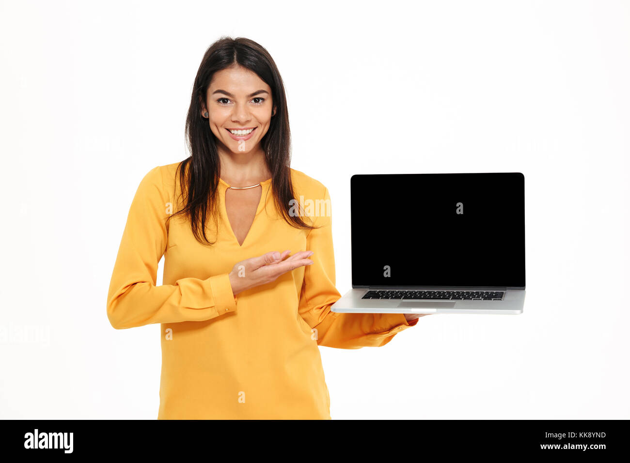 Portrait of a cheerful confident woman pointing at blank screen laptop ...