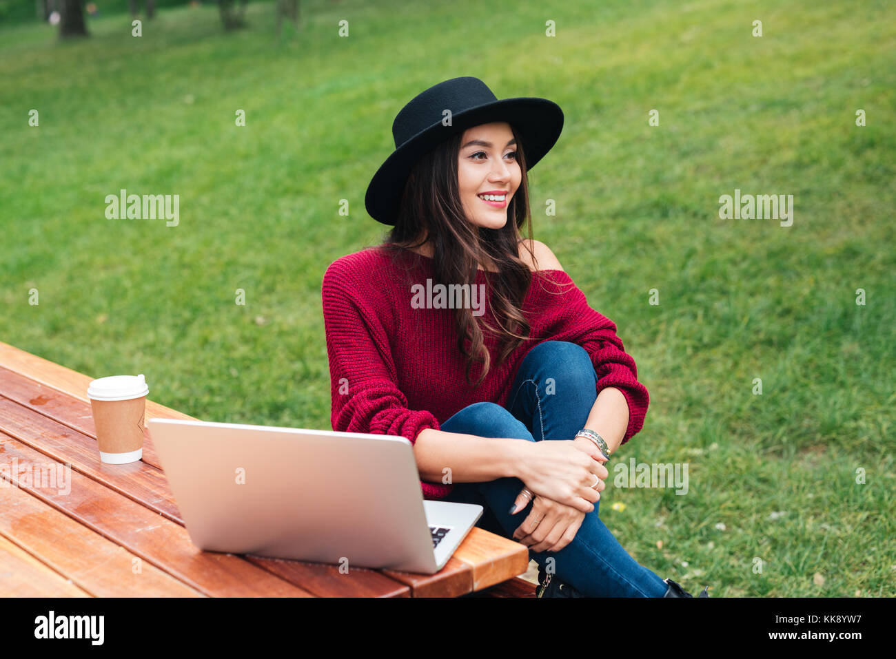 Portrait of a pretty cheerful asian girl using laptop computer while ...