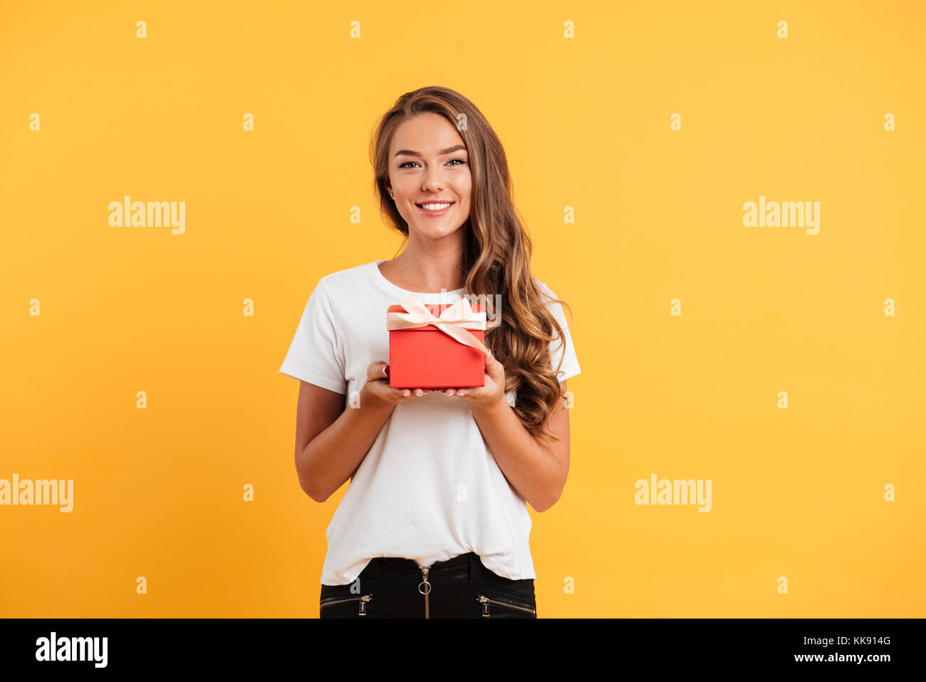 Portrait of a pretty smiling girl holding gift box and looking at ...