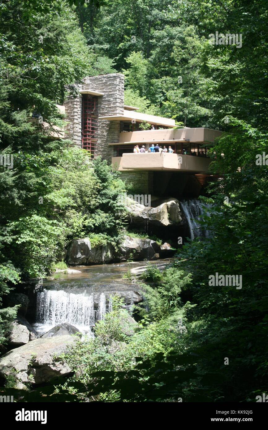 A photograph of the exterior of the home known as Fallingwater, a group of tourists stand on a balcony that overlooks the water falls the run under and around the home, Falling Water was built in 1935 by Frank Lloyd Wright, it is widely considered to be a significant piece of architecture, it was designated as a National Historic Landmark in 1966, Mill Run, Pennsylvania, 2014. Stock Photo