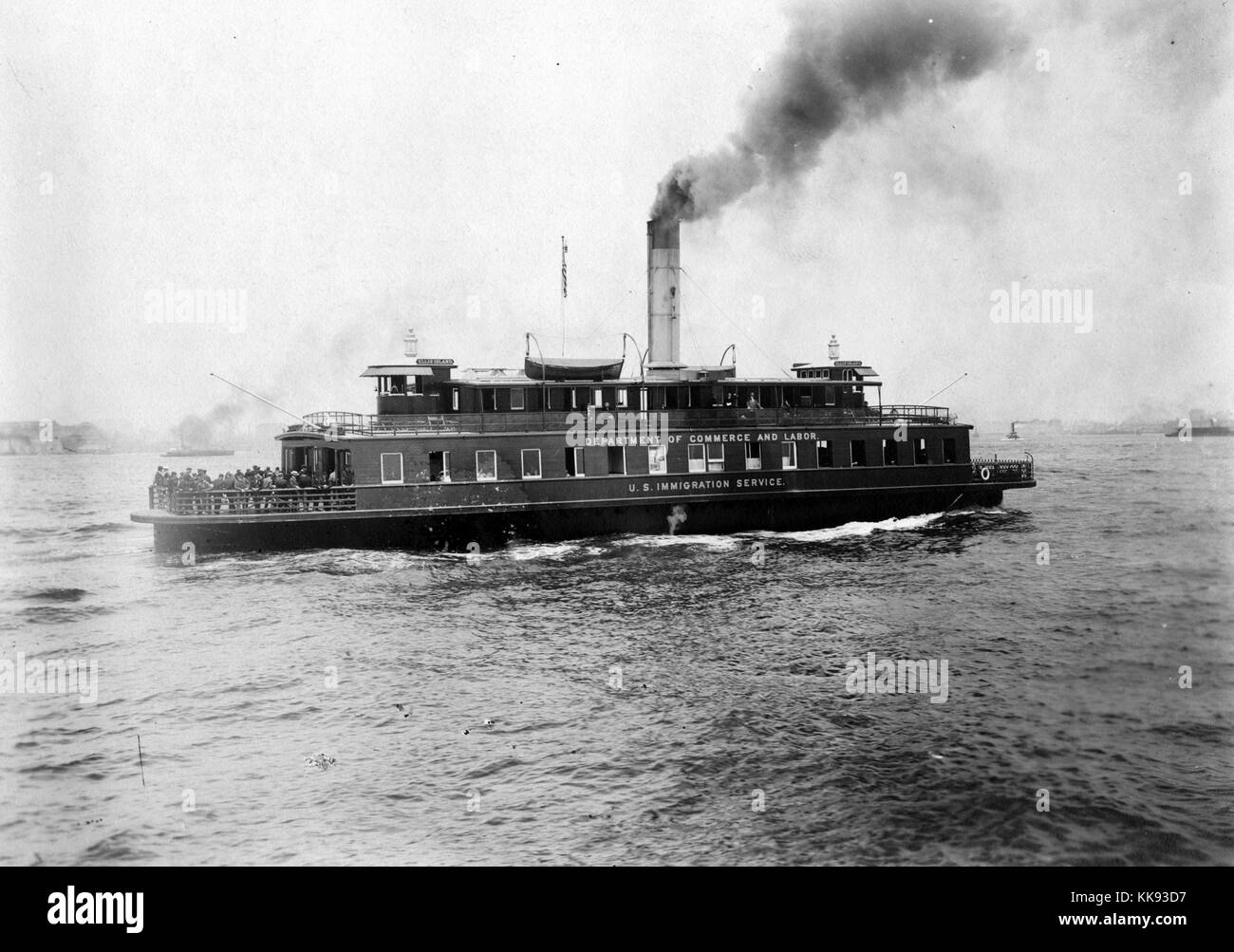 A photograph of a ship belonging to the Department of Commerce and Labor which operated the United States Immigration Service from 1903 until 1913, people can be seen standing in a large group at one end of the boat, the ferry provided transport to and from Ellis Island, over 12 million immigrants to the United States were processed on Ellis Island between 1892 and 1954, New York, 1907. From the New York Public Library. Stock Photo