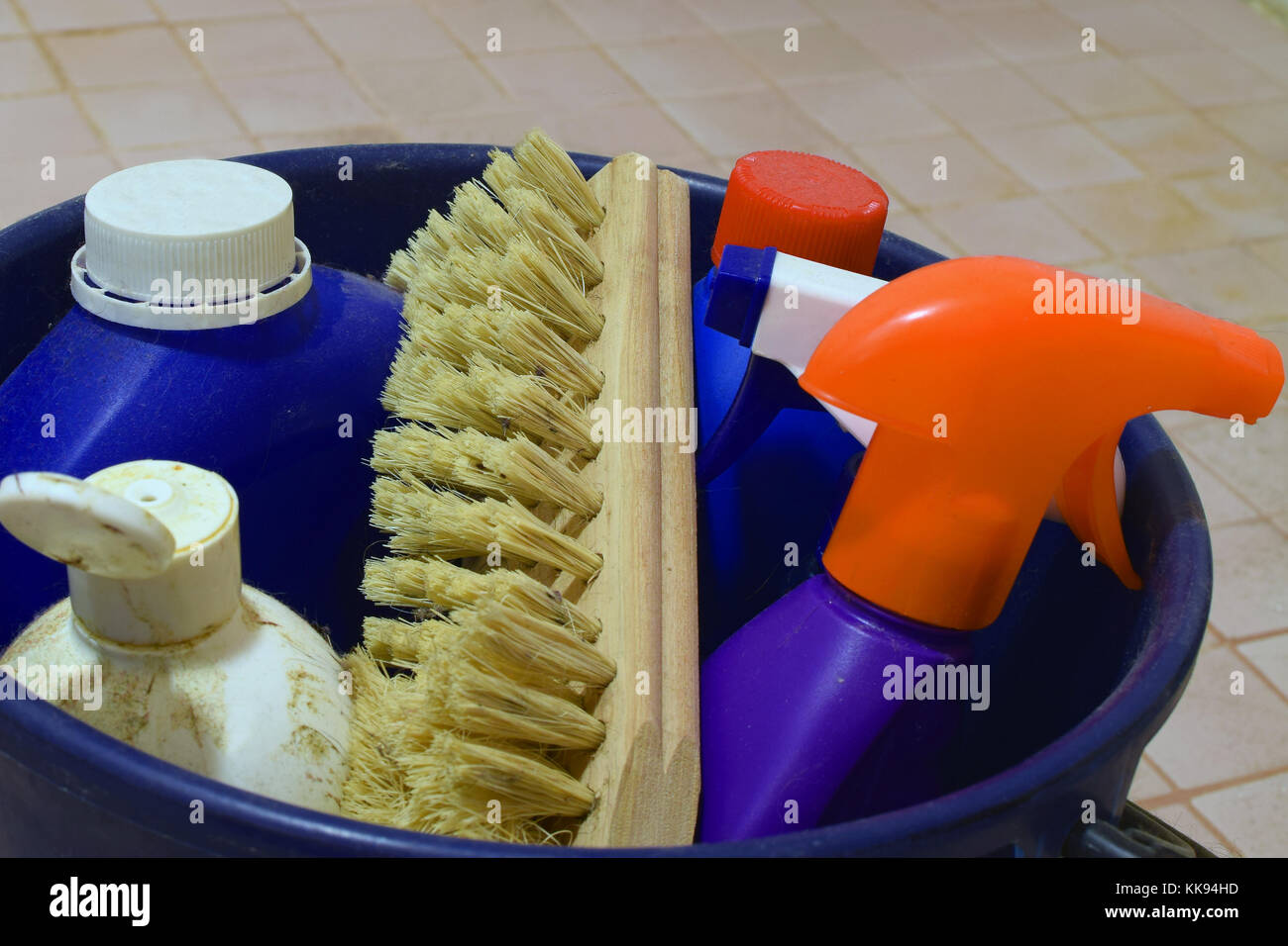 Close up of cleaning items in blue plastic bucket on dirty bathroom