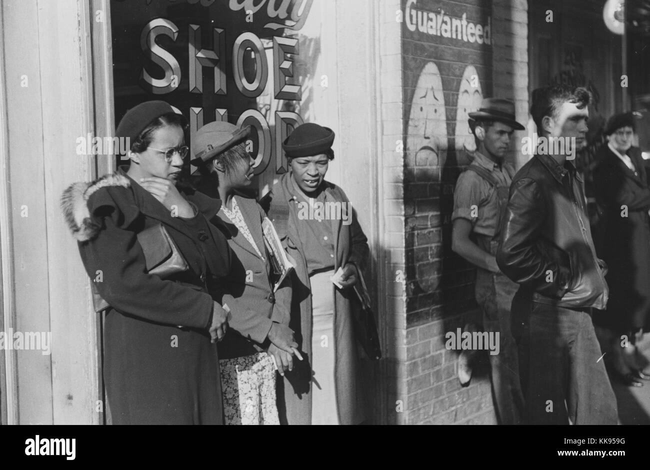 A photograph of three African American women who were identified as domestic helpers waiting for a street car, all three women are wearing coats and hats, two men and a woman who are white are also waiting on transportation, Atlanta, Georgia. 1939. From the New York Public Library. Stock Photo