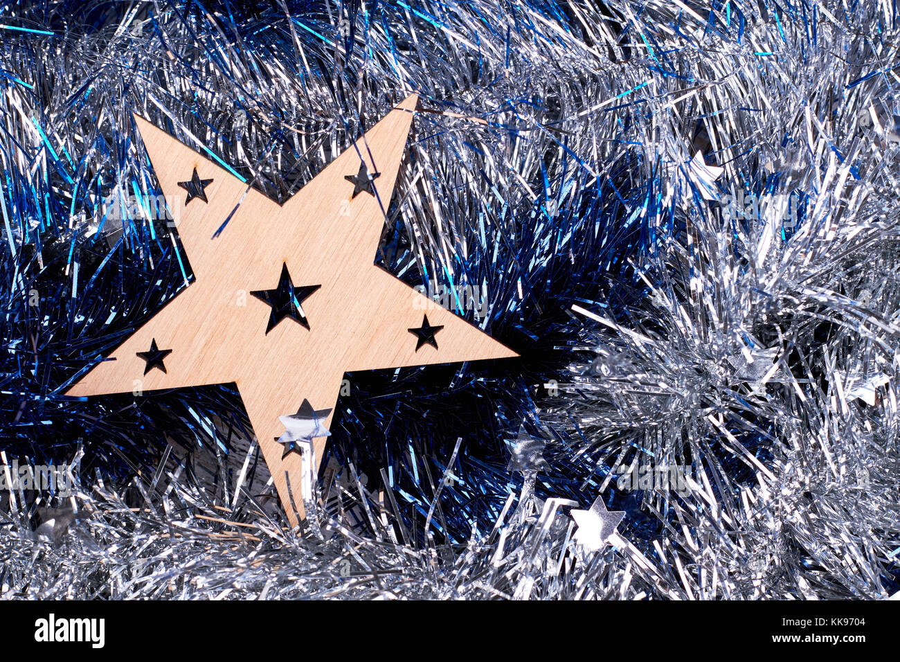 Cut out wooden star on tinsels background. Stock Photo
