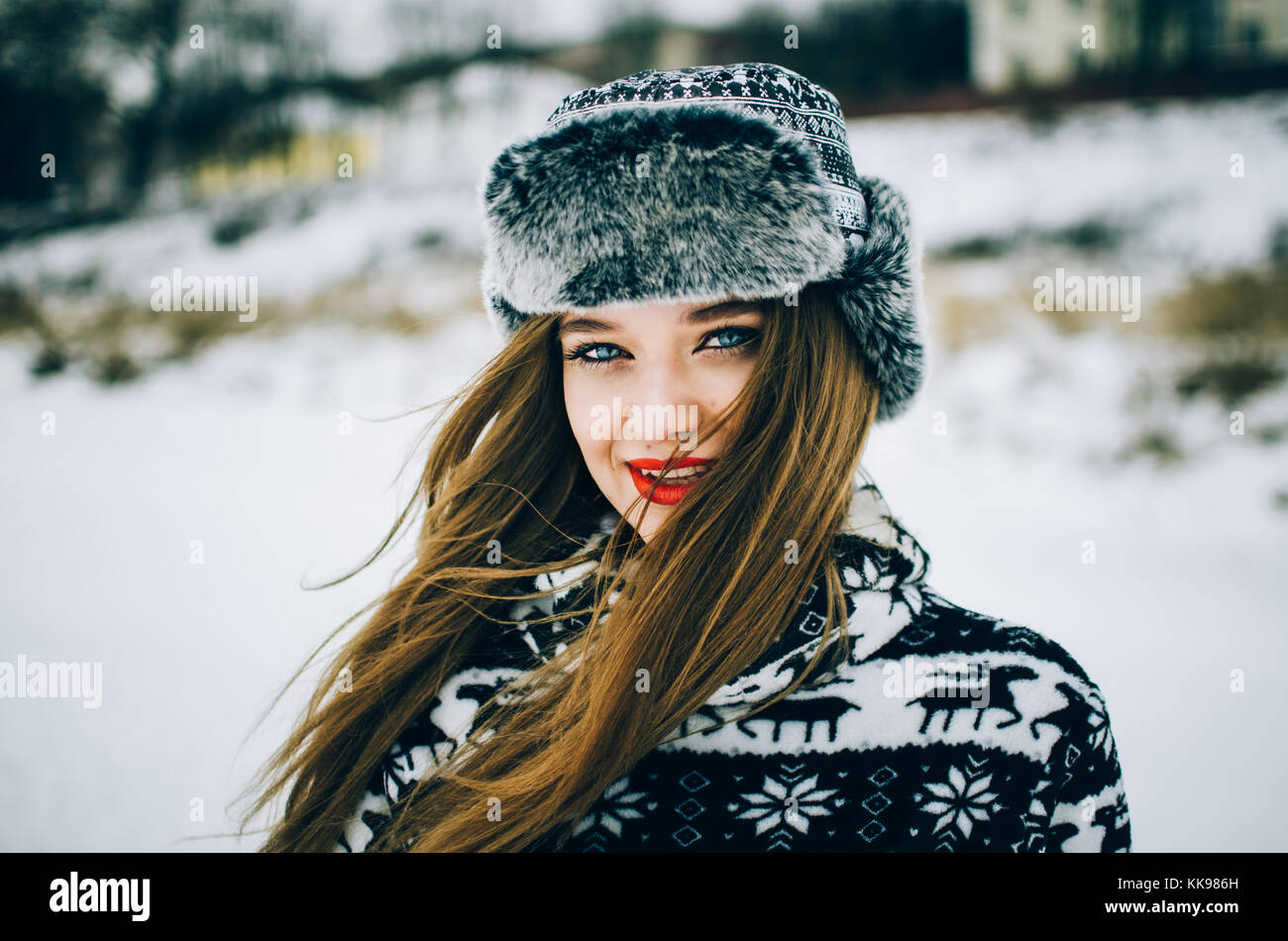 Portrait of handsome young woman with blue eyes looking camera and wearing warm hat in winter. Stock Photo