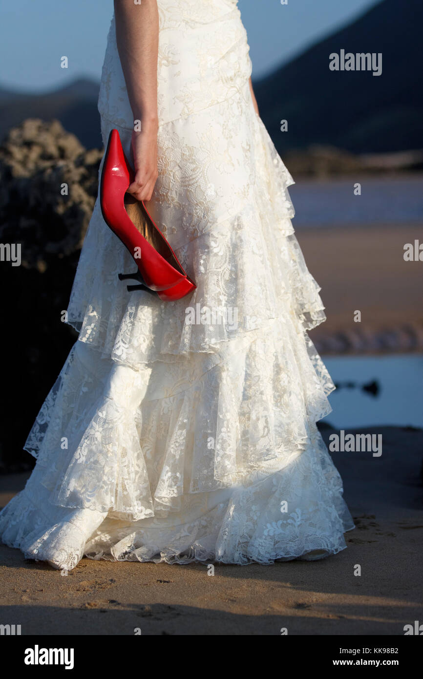 Bride holding red shoes. Stock Photo