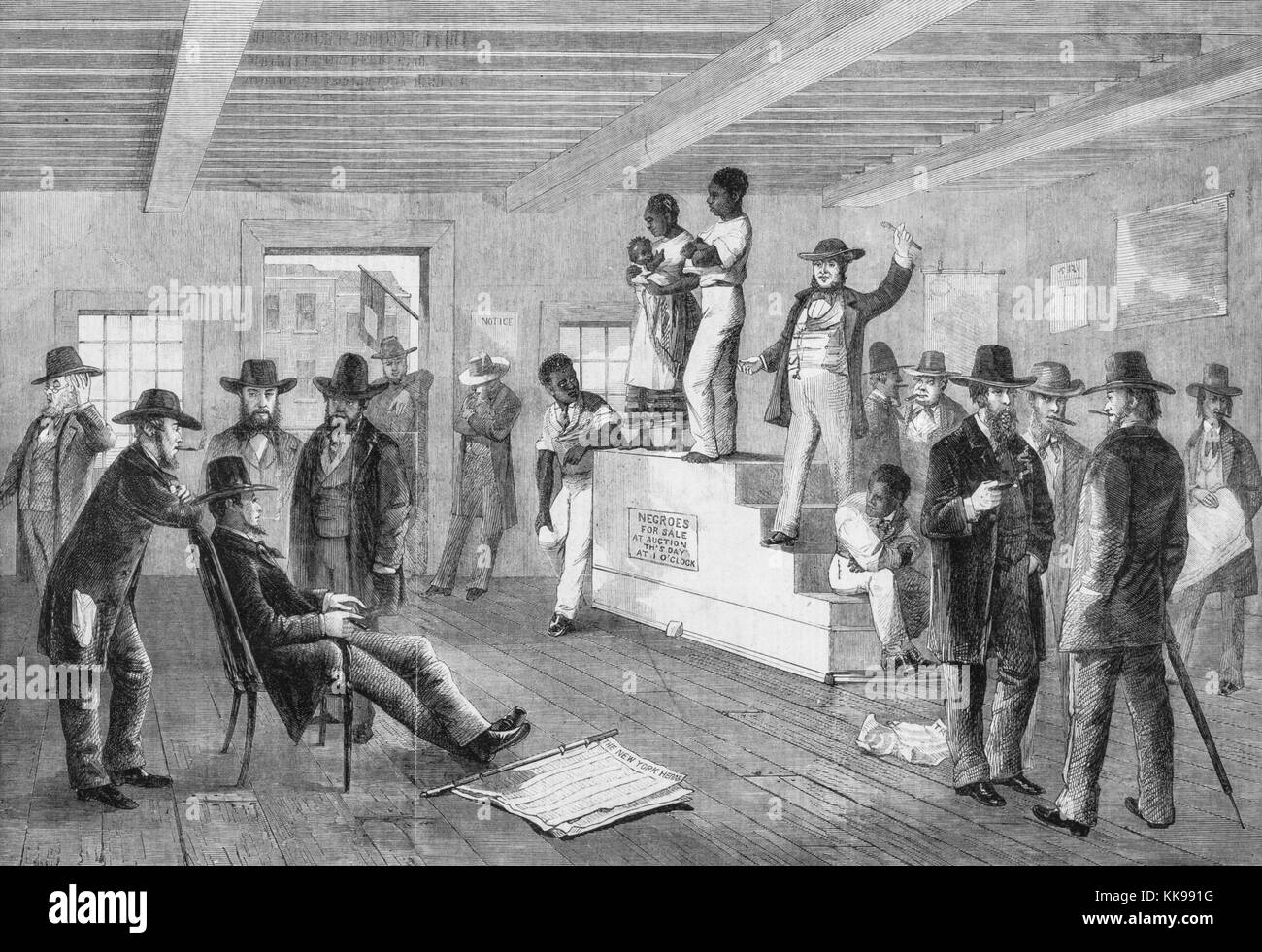 An etching from a painting of a slave auction, a black man stands next to a black woman holding her child on top of a raised platform, two other black men are seen leaning and sitting on the edges of the platform, a white auctioneer addresses the crowd of white men from the platform, the other men are standing and conversing throughout the room, Virginia, 1861. From the New York Public Library. Stock Photo