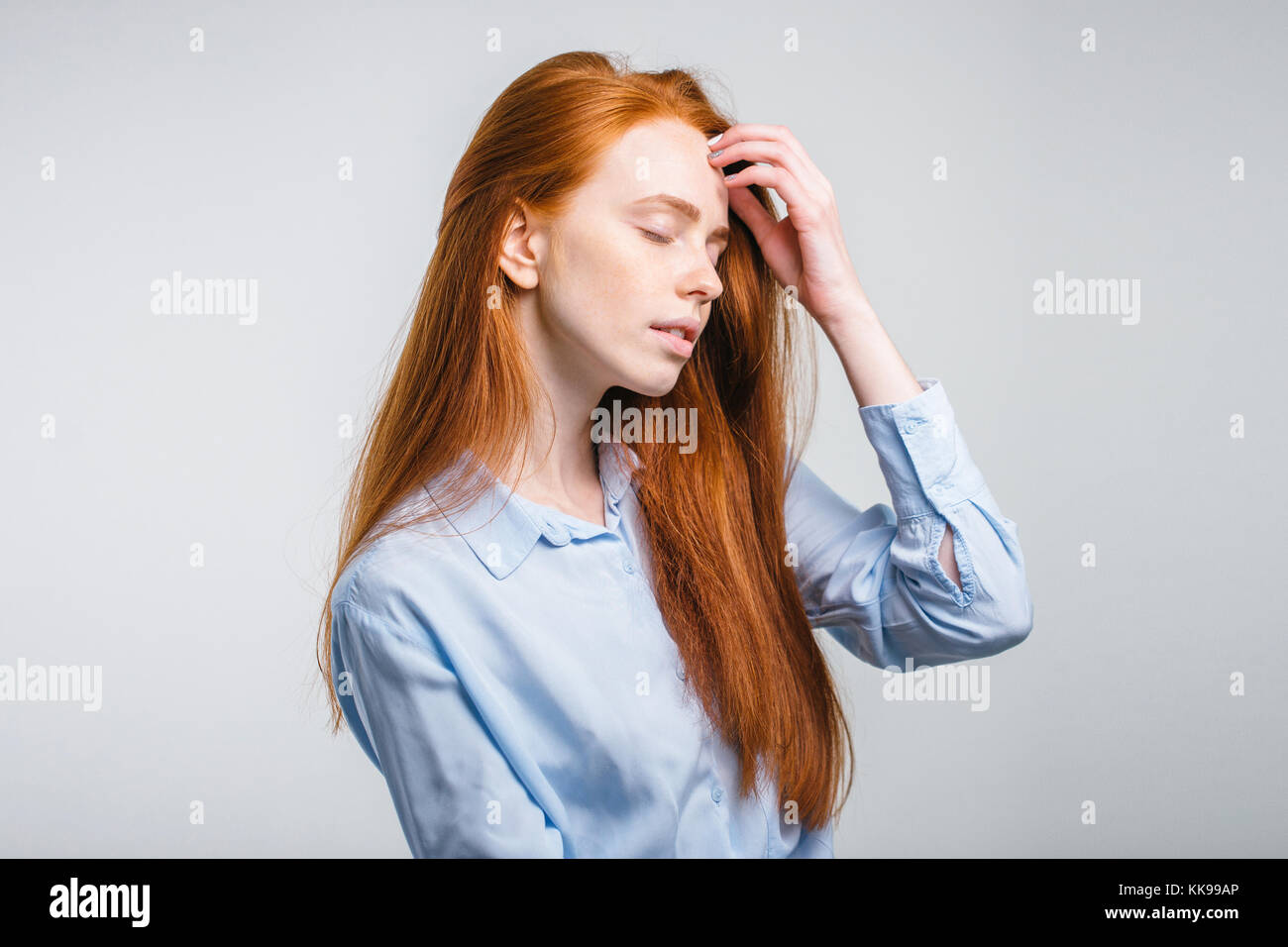 girl with freckles smiling with closed eyes touching her red hair Stock Photo