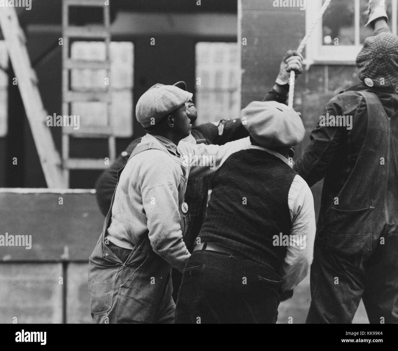 Black and white photograph of a group of African-American Emergency Defense Office, a United States federal emergency war agency set up to coordinate state and federal measures for protection of civilians in case of war emergency, construction workers pulling on a rope, Washington, DC, December, 1941. From the New York Public Library. Stock Photo
