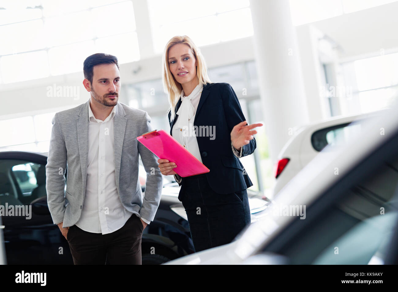 Professional salesperson selling cars at dealership to buyer Stock Photo