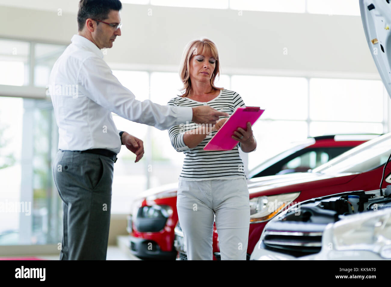 Professional salesperson selling cars at dealership to buyer Stock Photo