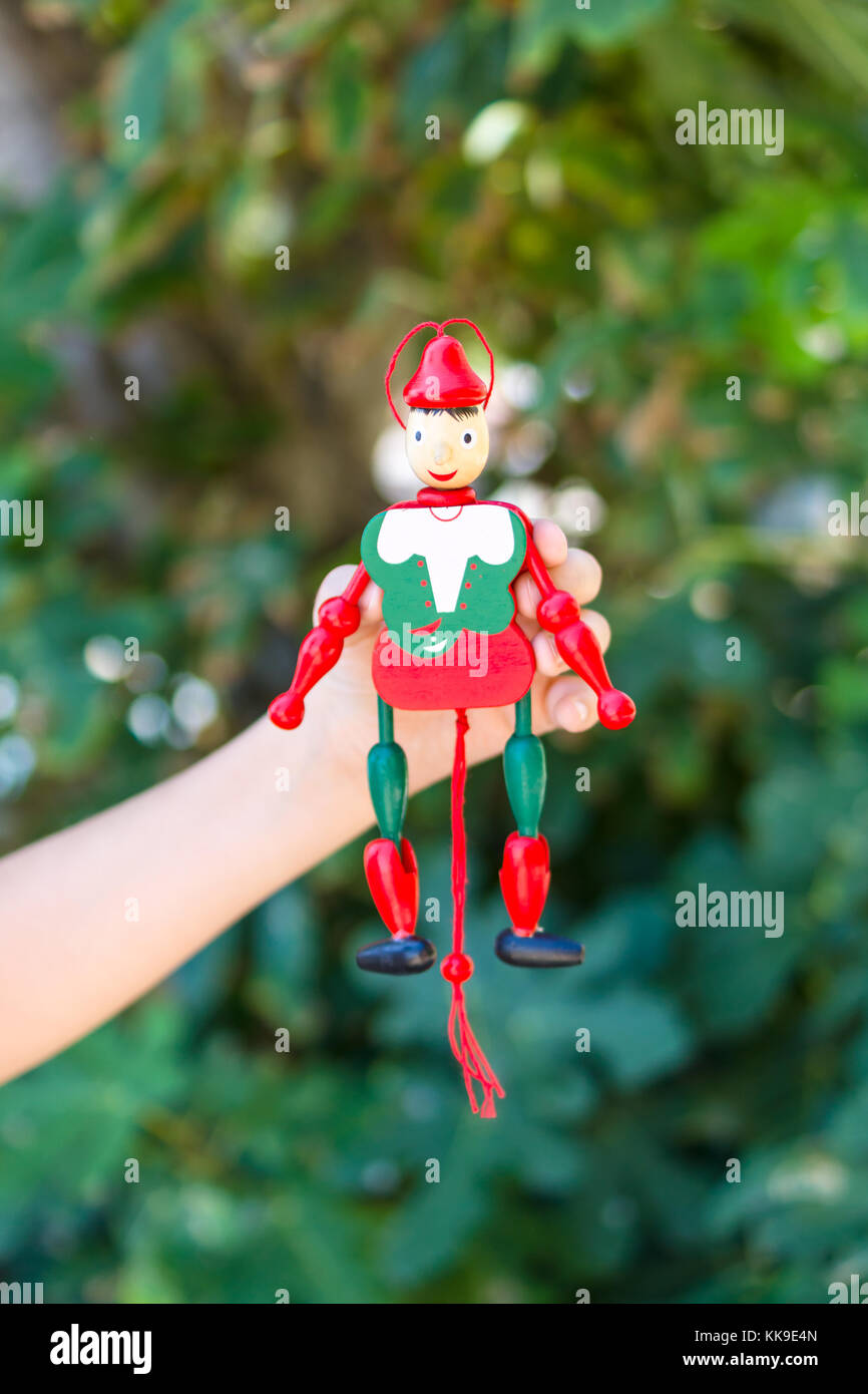 A wooden toy of Pinocchio in children's hands. Stock Photo
