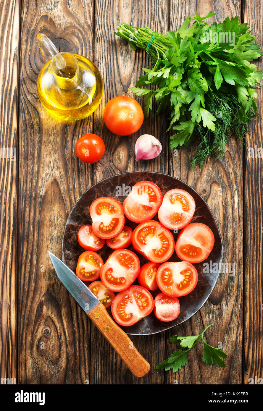 fresh tomato with salt and basil on the kitchen table Stock Photo - Alamy