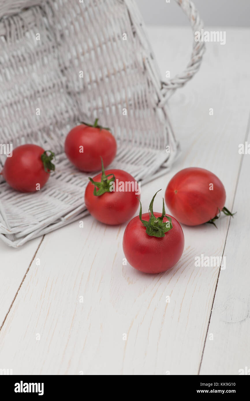 tomatoes in a white basket on a white background Stock Photo - Alamy