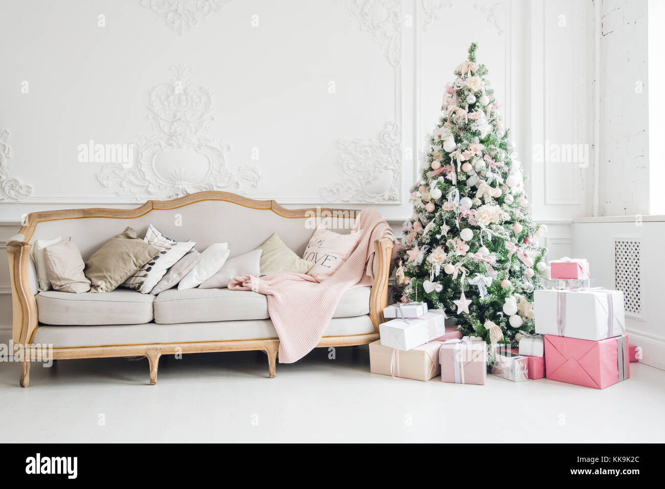 New Year's holiday or celebration, the mood, Stylish Christmas minimalistic interior, Presents and wrapped gifts under the Christmas tree. large white living room with a vintage sofa Stock Photo