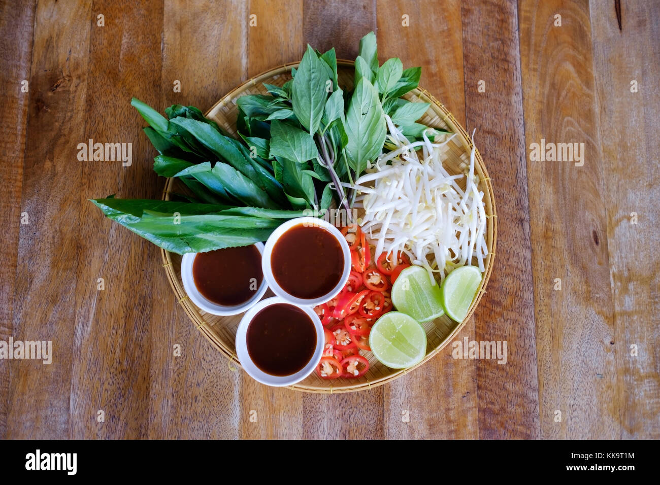 Traditional Vietnamese food. Fresh herbs. Plates on a wooden surface. Stock Photo