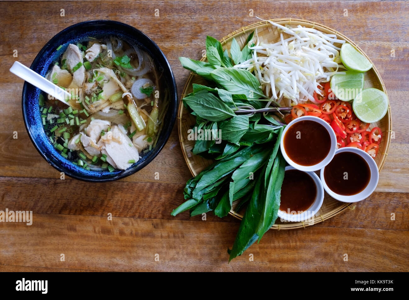 Traditional Vietnamese food. Soups, rolls and fresh herbs. Plates on a wooden surface. Stock Photo