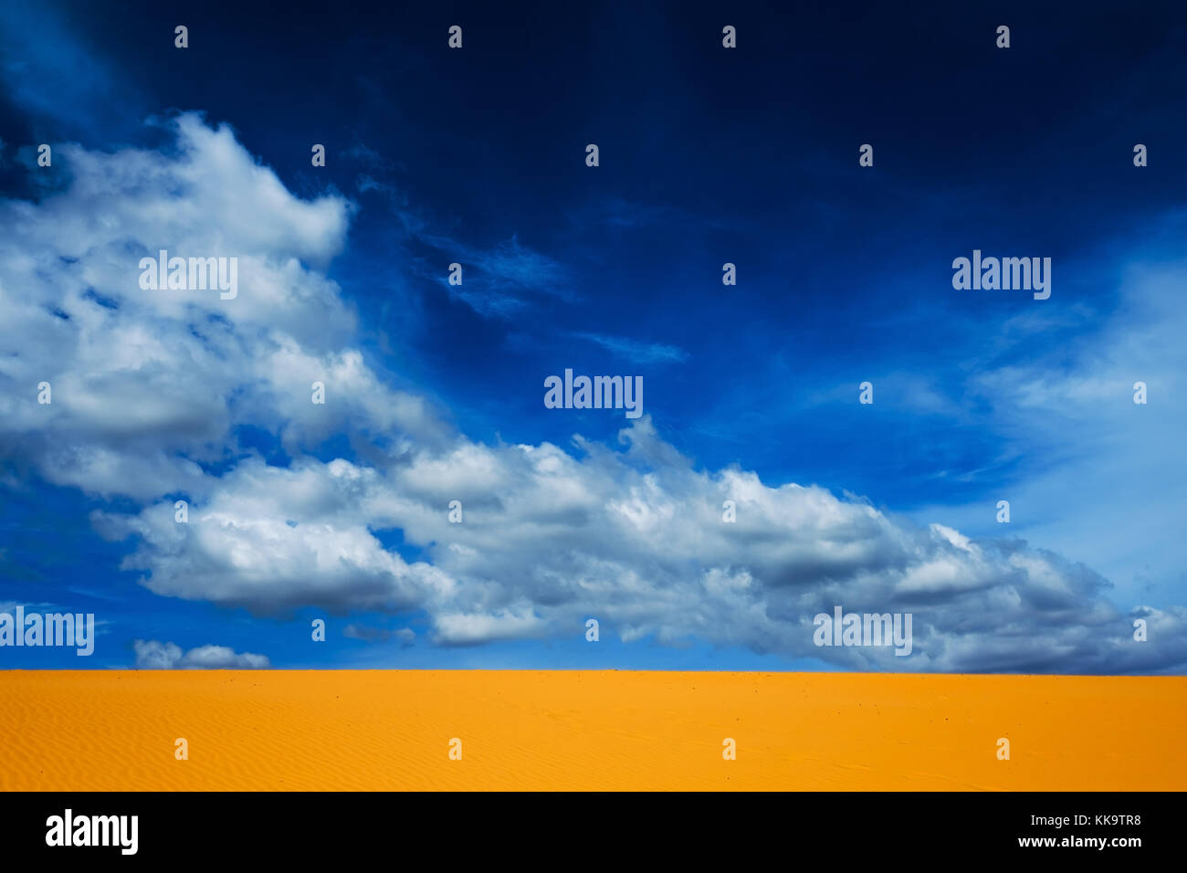 Bright yellow sand empties against the blue sky with clouds. Stock Photo