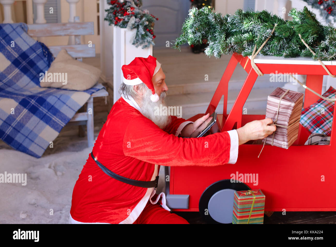 Santa Claus checking list of presents on tablet and putting gift Stock ...
