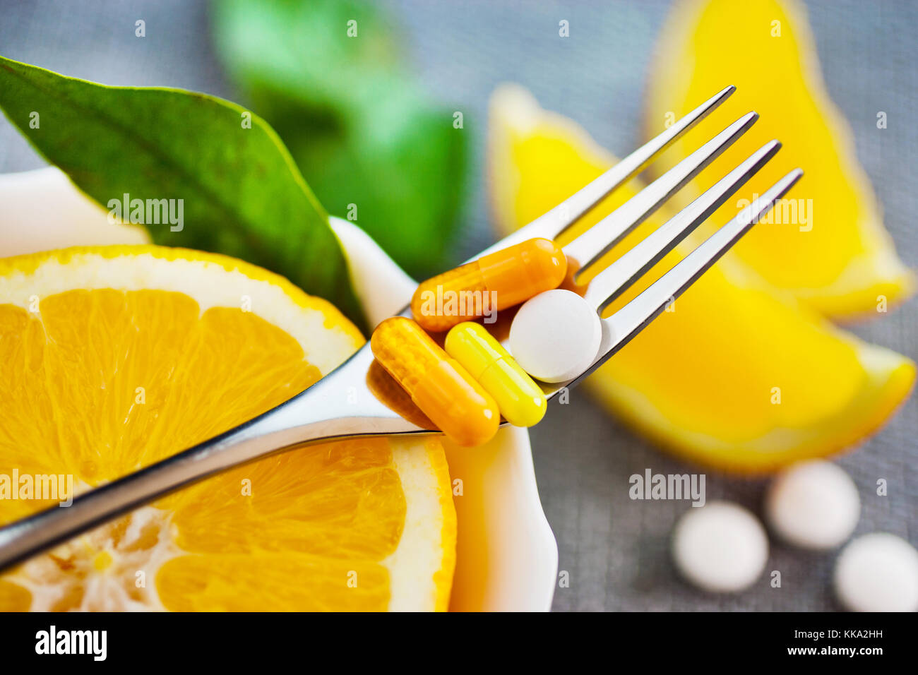 health care - fresh orange fruit and vitamin C - nutition tablets on the fork Stock Photo