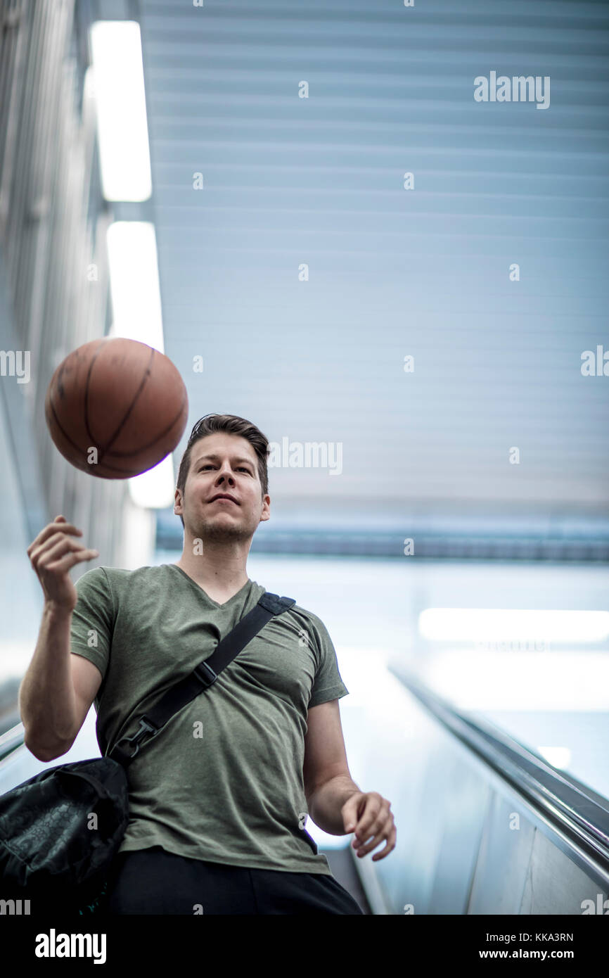 A man walking down a stairwell with a basketball in hand. Low angle shot. Stock Photo