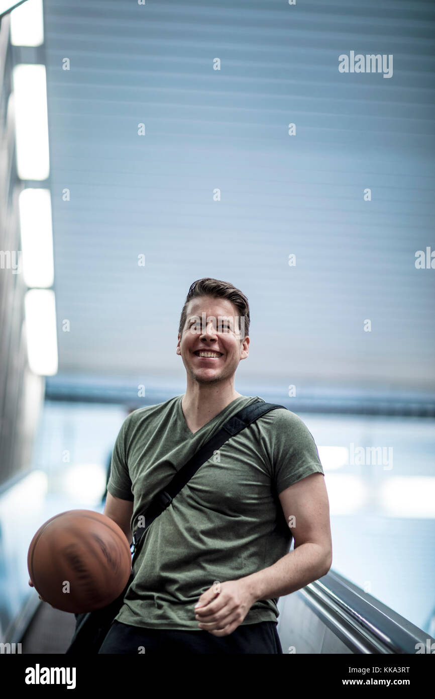 A man walking down a stairwell with a basketball in hand. Low angle shot. Stock Photo