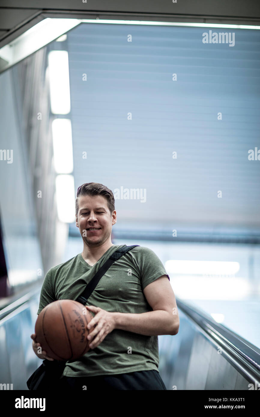 A man walking down a stairwell with a basketball in hand. Low angle shot. Stock Photo