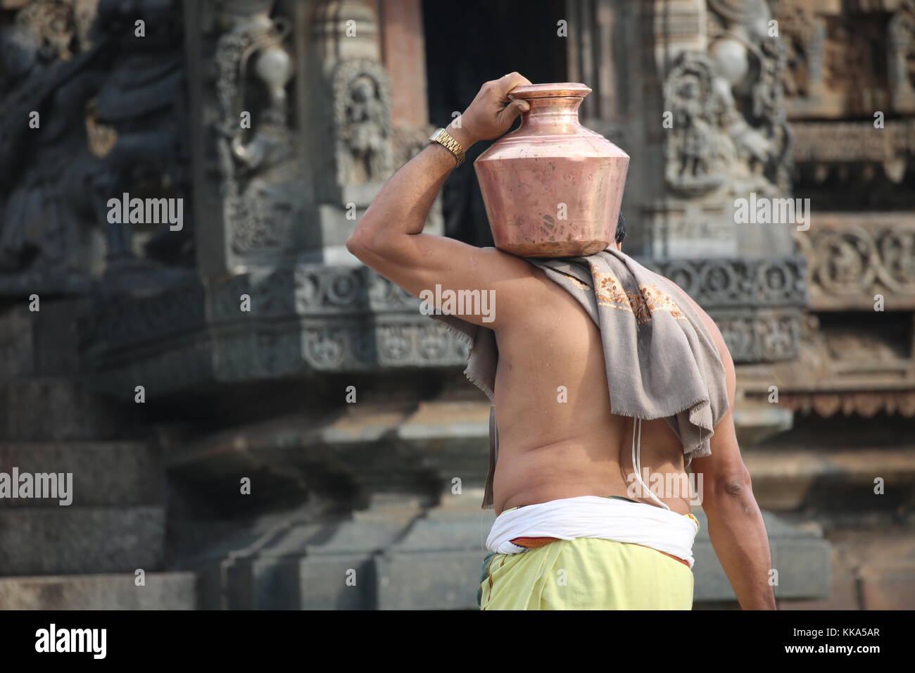 Morning in Chenna Keshava Vishnu Temple - priest with lota kalash pot making offerings - Priester mit Kuferkrug beim Wasser holen Stock Photo