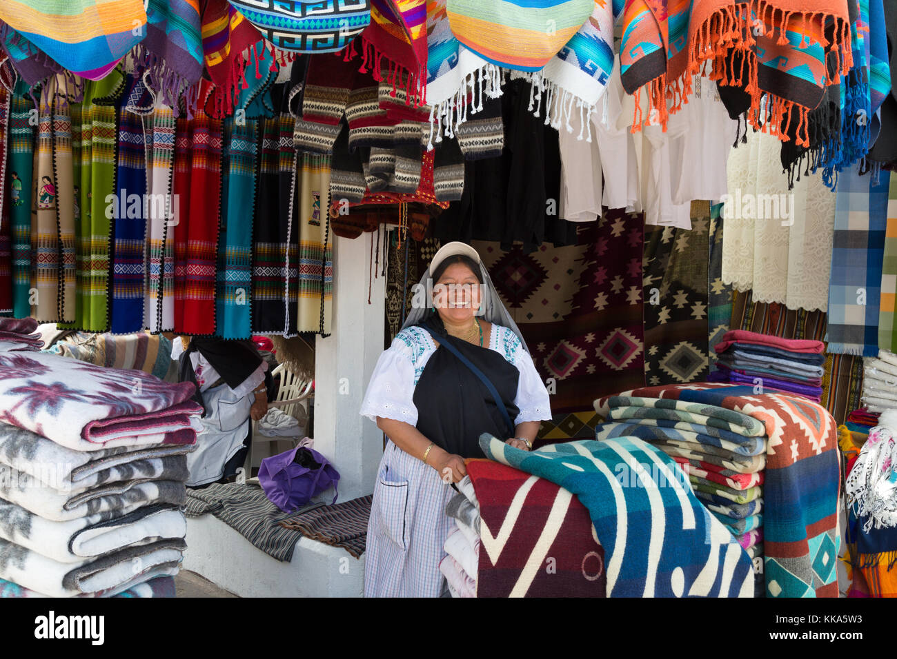 A happy smiling vendor and her clothes market stall, Otavalo market, Ecuador latin America Stock Photo