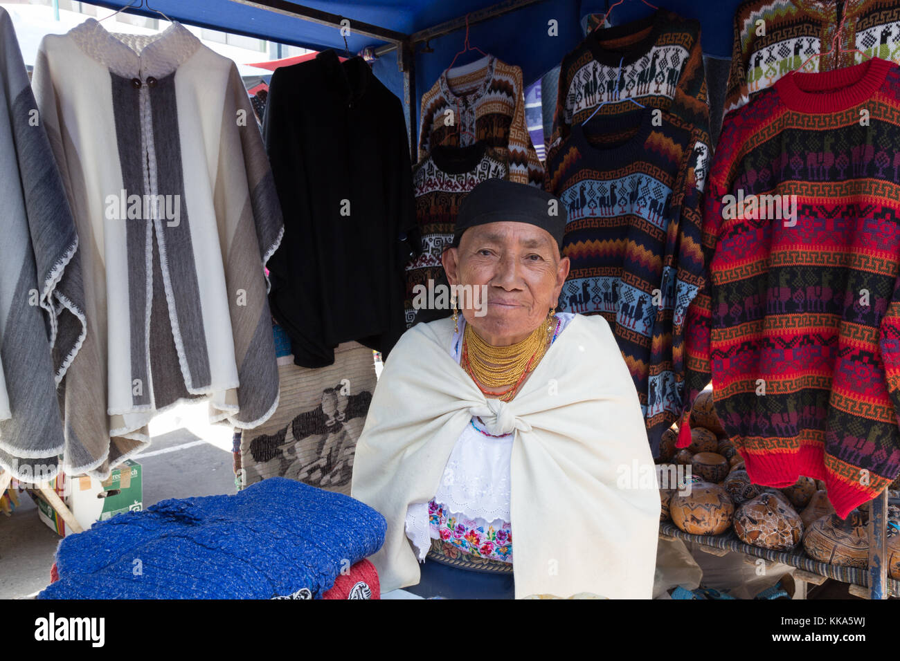 Indigenous woman stall holder i=and her clothes stall, Otavalo Market, Ecuador South America Stock Photo