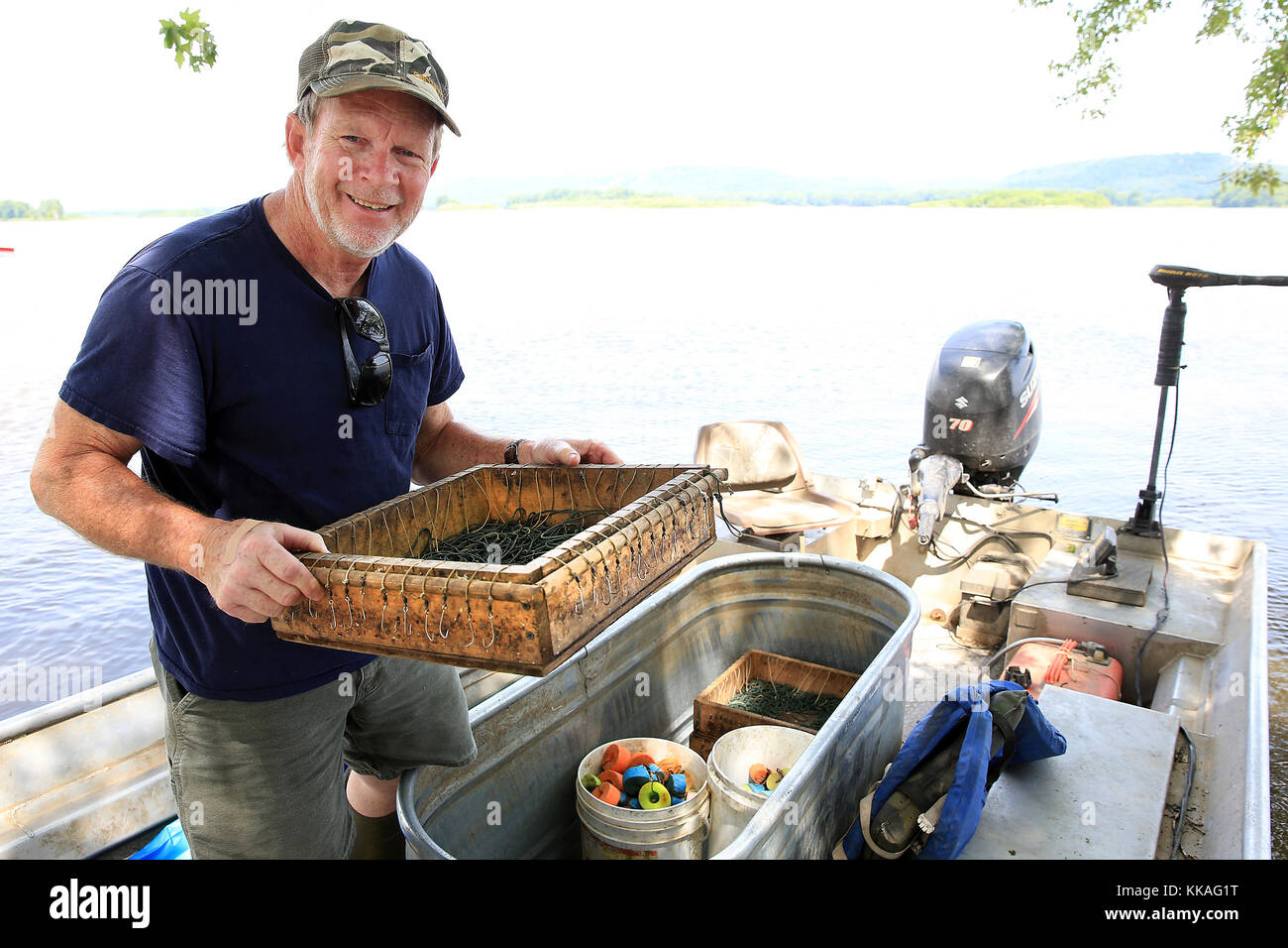 Bellevue, Iowa, USA. 6th July, 2017. Commercial fisherman Dennis Weiss of Bellevue loads a box containing one of his trotlines into his boat before heading out for the afternoon on the Mississippi River to set trotlines from the Spruce Creek Harbor near Bellevue, Iowa July 6, 2017. (A trotline is a length of line stretched with the use of a boat, across a section of water and fastened secure at both ends. On the line every three or four feet a hook is dangled from a drop line, essentially making it impossible for a catfish to swim by the line without being tempted by one of the baited hooks. Stock Photo