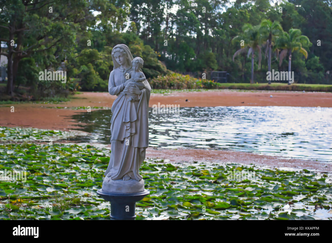 A statue of the Blessed Virgin Mary and the child Jesus in the man-made lagoon of a school compound. Stock Photo