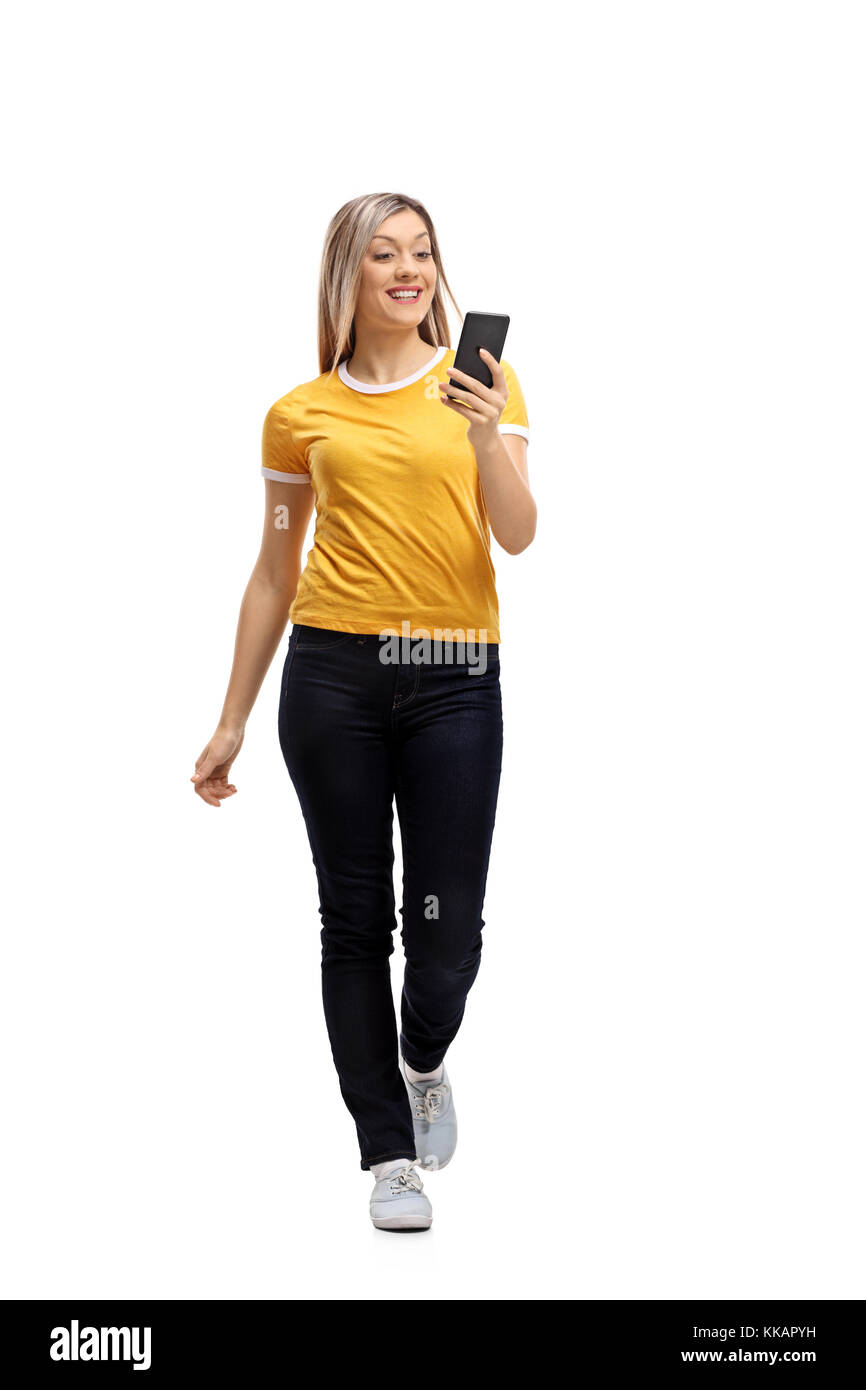 Full length portrait of a young woman walking and using a phone isolated on white background Stock Photo