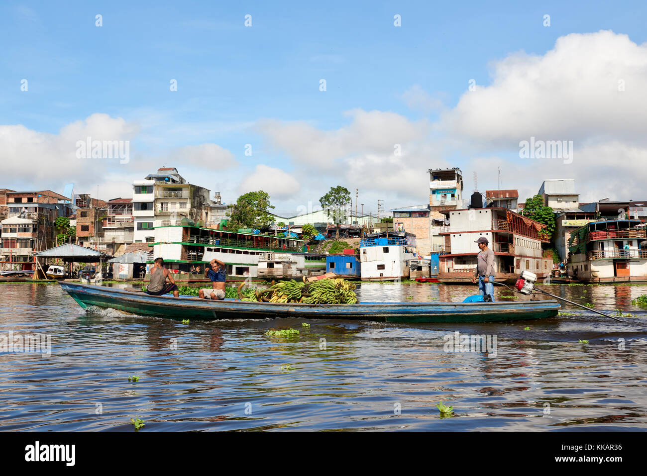 Salesmen transporting a load of bananas on riverboat in Nanay River, with city of Iquitos, in the background, Peru, South America Stock Photo
