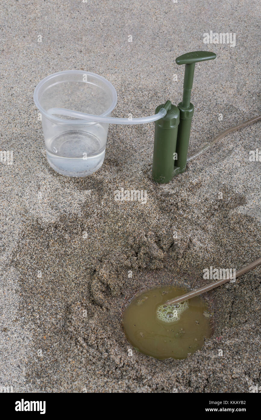 Personal water purification pump in sandy environment. Metaphor for survival / desert survival. Behind enemy lines concept, water harvesting. Stock Photo