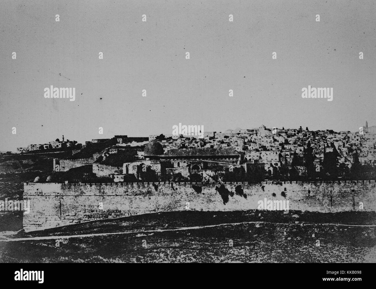 Black and white photograph of a walled city, from the outside, titled 'Enceinte du temple, vue generale de la face est, Plate 1', by Auguste Salzmann, 1856. From the New York Public Library. Stock Photo