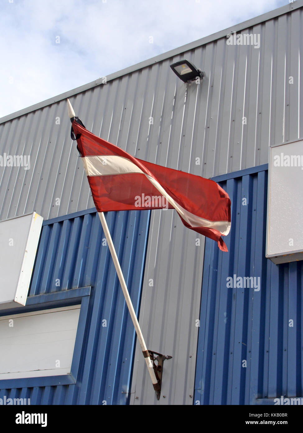 Latvia national flag with black mourning ribbon waving on building wall ...