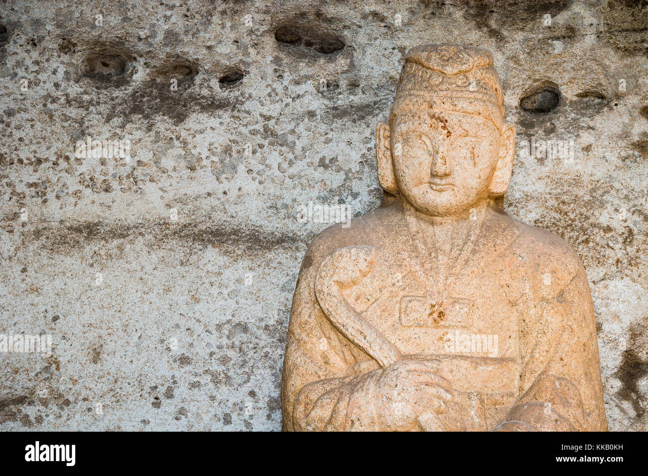 A sculpture of  Buddha carved into a beige colored stone Stock Photo