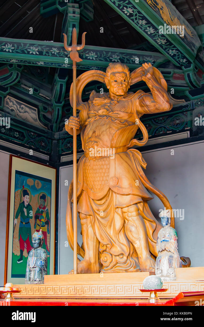 Buddhist diety, giant statue carved in wood and house in a temple. Stock Photo