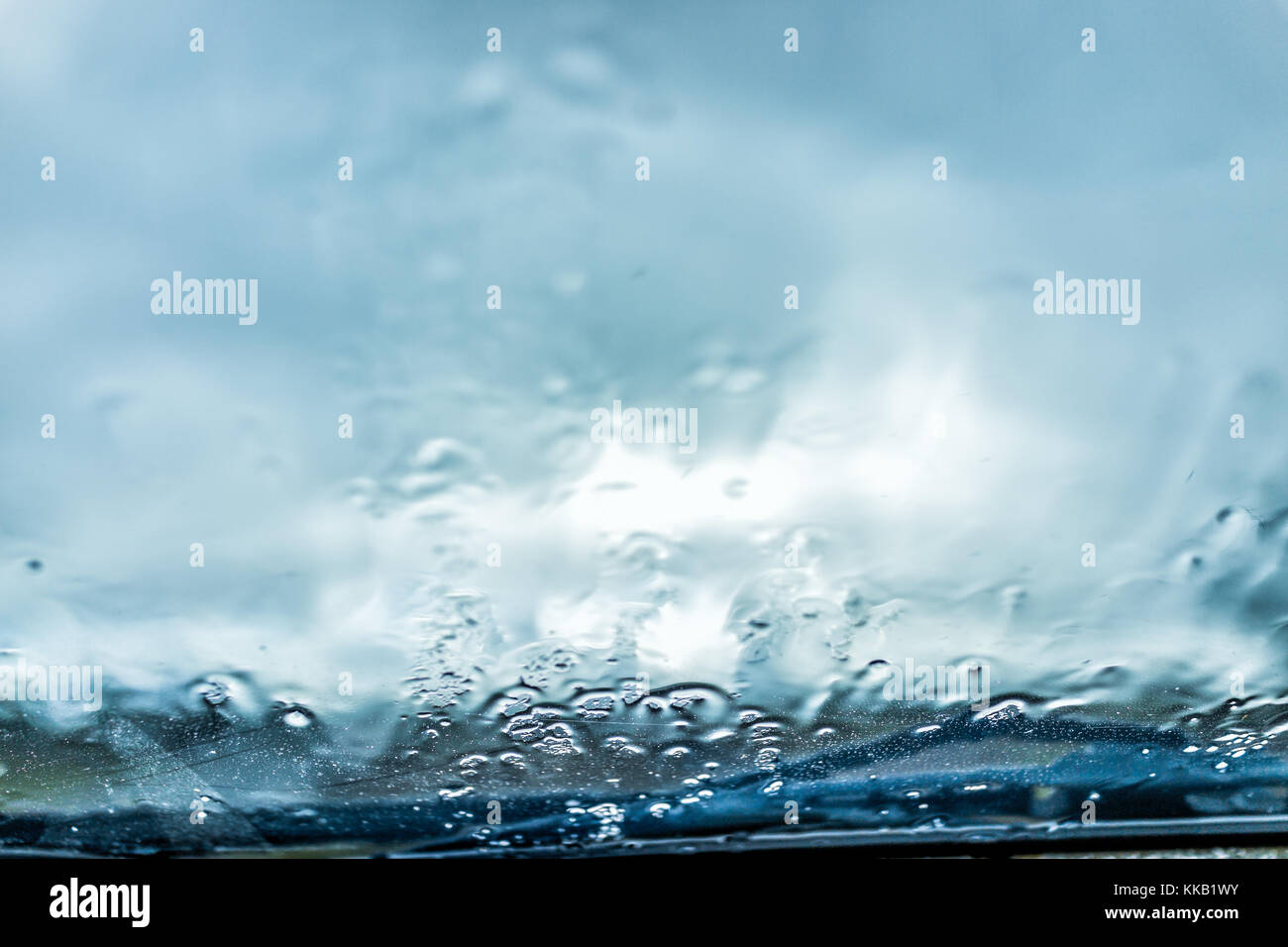 Macro closeup of wet car windshield glass window with hail rain falling
