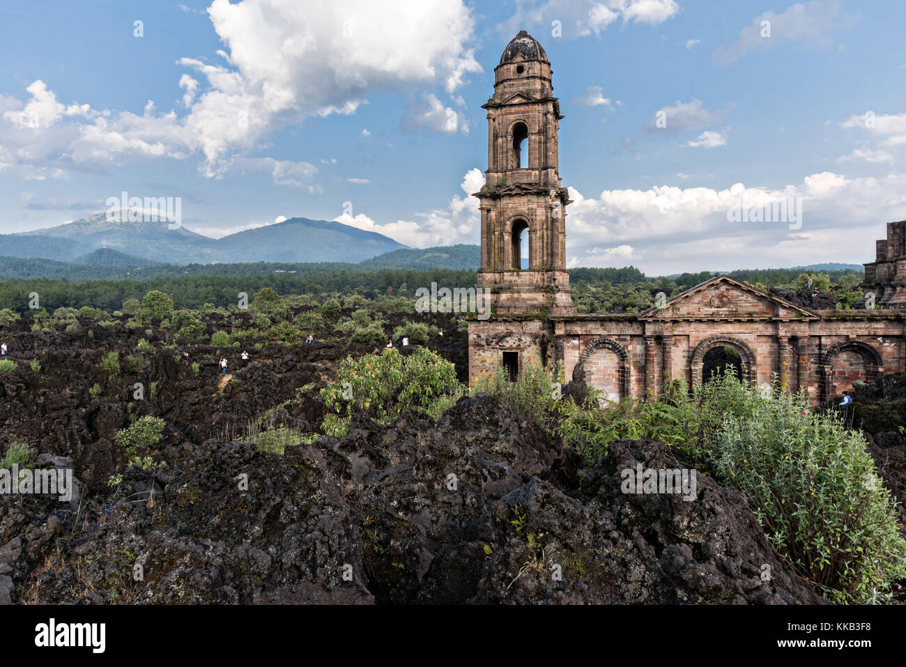 The steeple of San Juan Parangaricutiro church pokes up out of a sea of dried lava rock in the remote village of San Juan Parangaricutiro, Michoacan, Mexico. This church is the only remaining structure left buried in the eight-year eruption of the Paricutin volcano which consumed two villages in 1943 and covered the region in lava and ash. Stock Photo