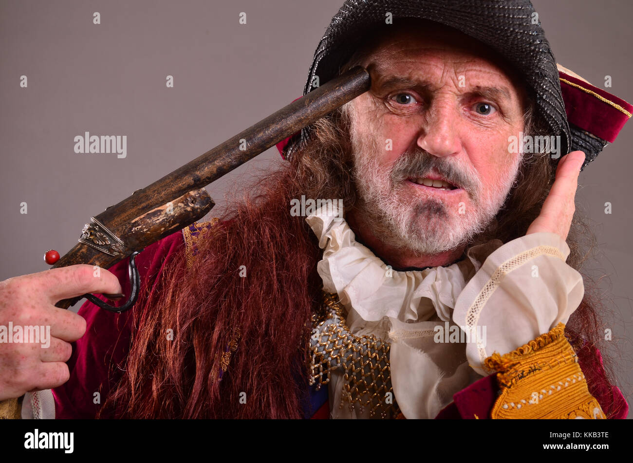 Portrait of old captain pirate, holding his gun pointed to his head, ready to commit suicide Stock Photo