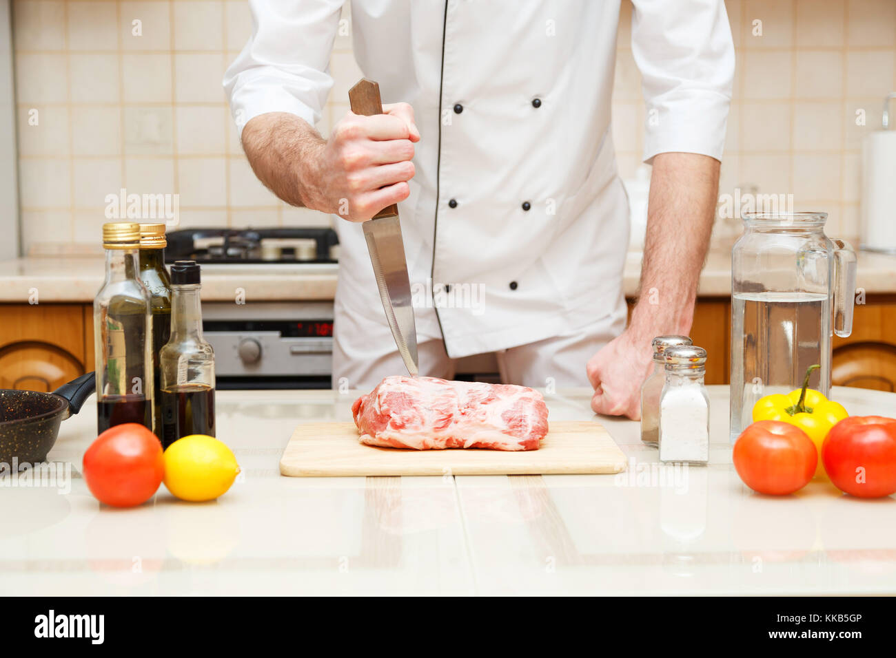 Butcher cutting meat on chopping board, professional cook holding knife