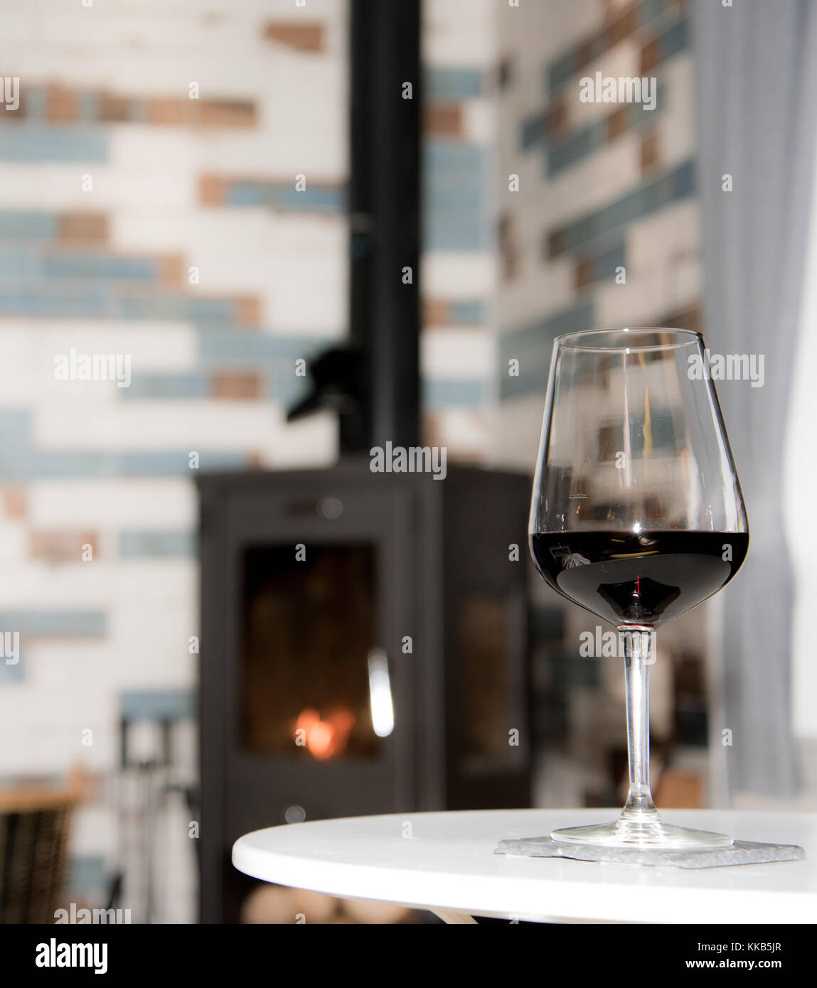 Glass of red wine and fire in stove - romantic living room scenery Stock Photo
