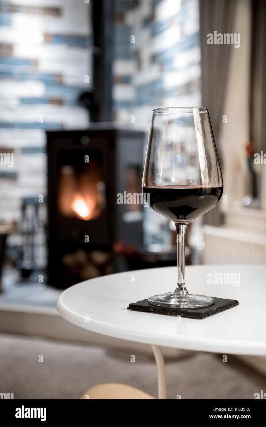 Glass of red wine and fire in stove - romantic living room scenery Stock Photo