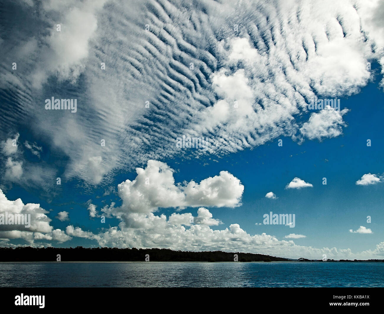 A spectacular inspirational brightly coloured cloudy sea water tropical seascape featuring  white Altocumulus cloud formation (AKA. Mackerel Sky) Stock Photo