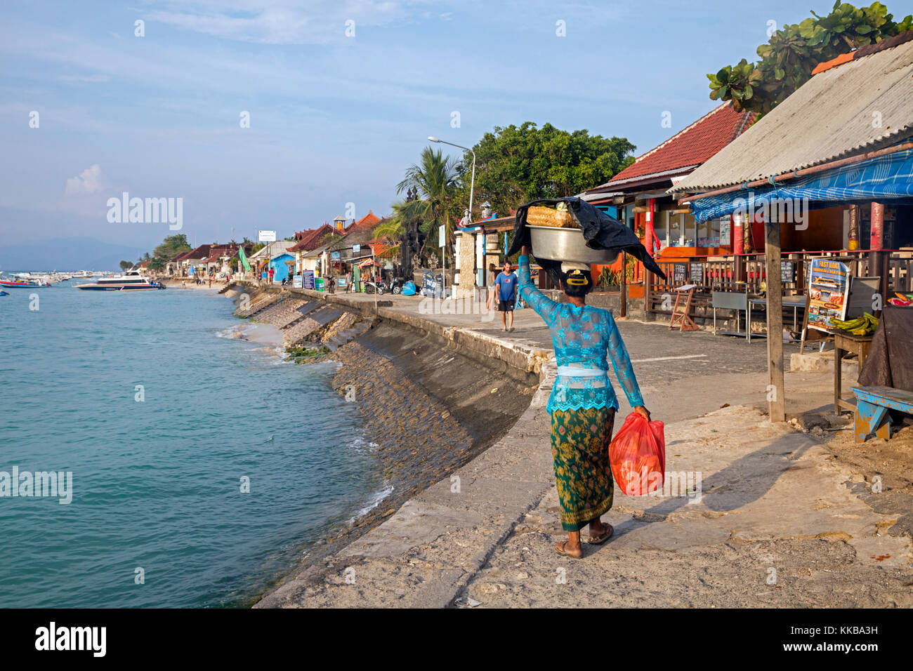 Indonesian woman carrying merchandise on her head in the coastal village Jungut Batu / Jungutbatu on the island Nusa Lembongan near Bali in Indonesia Stock Photo