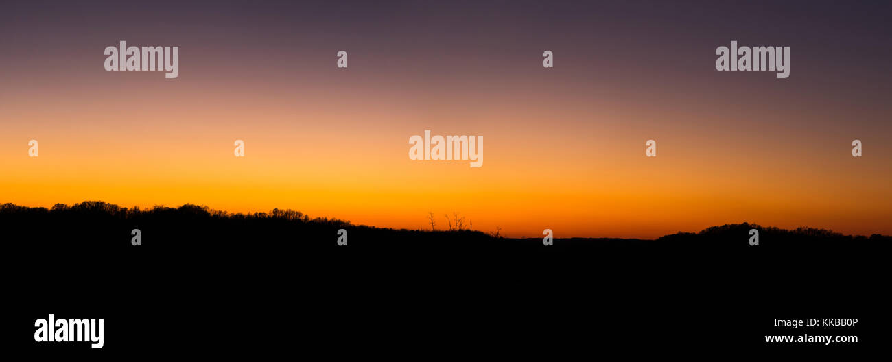 The colors of sunset are shown above the silhouette of a mountainous ridge line. Stock Photo